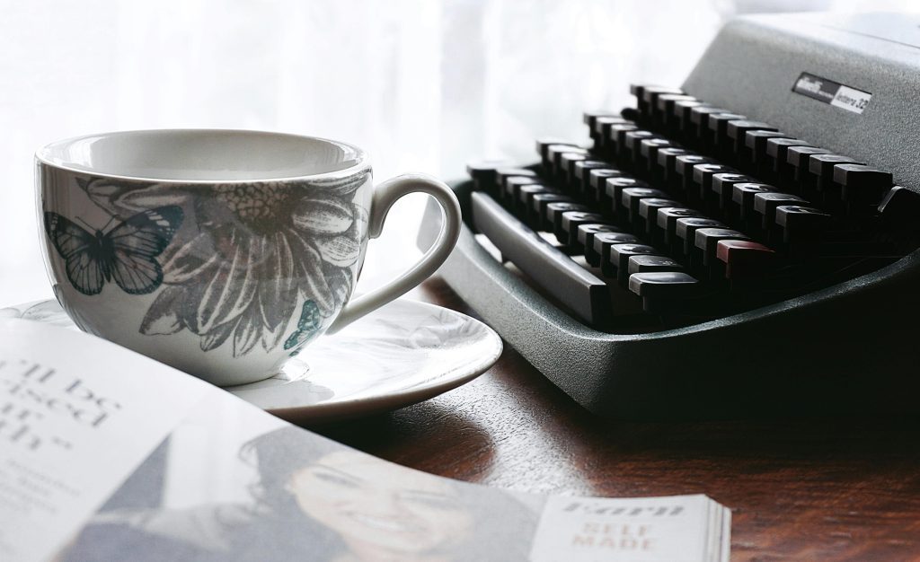 A nostalgic desk scene with a typewriter and floral teacup, evoking retro vibes.
